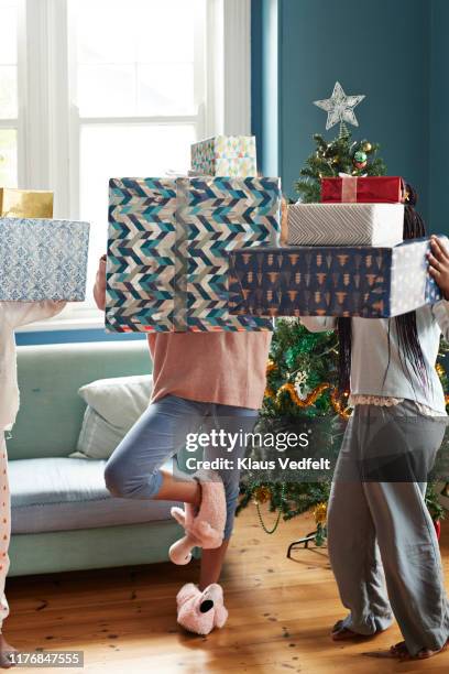 sisters carrying christmas gifts in living room - carrying photos et images de collection