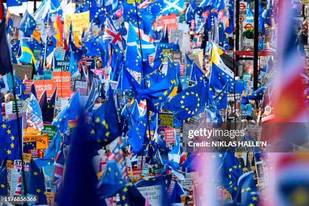 Demonstrators hold placards and EU and Union flags as they take part in a march by the People's Vote organisation in central London on October 19...