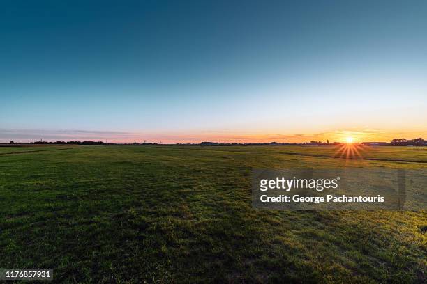 sunset over a grass field - horizon over land stock pictures, royalty-free photos & images
