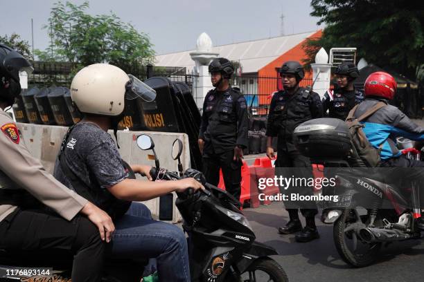 Motorists travel past police officers standing guard near the National Parliament complex ahead of the presidential inauguration in Jakarta,...