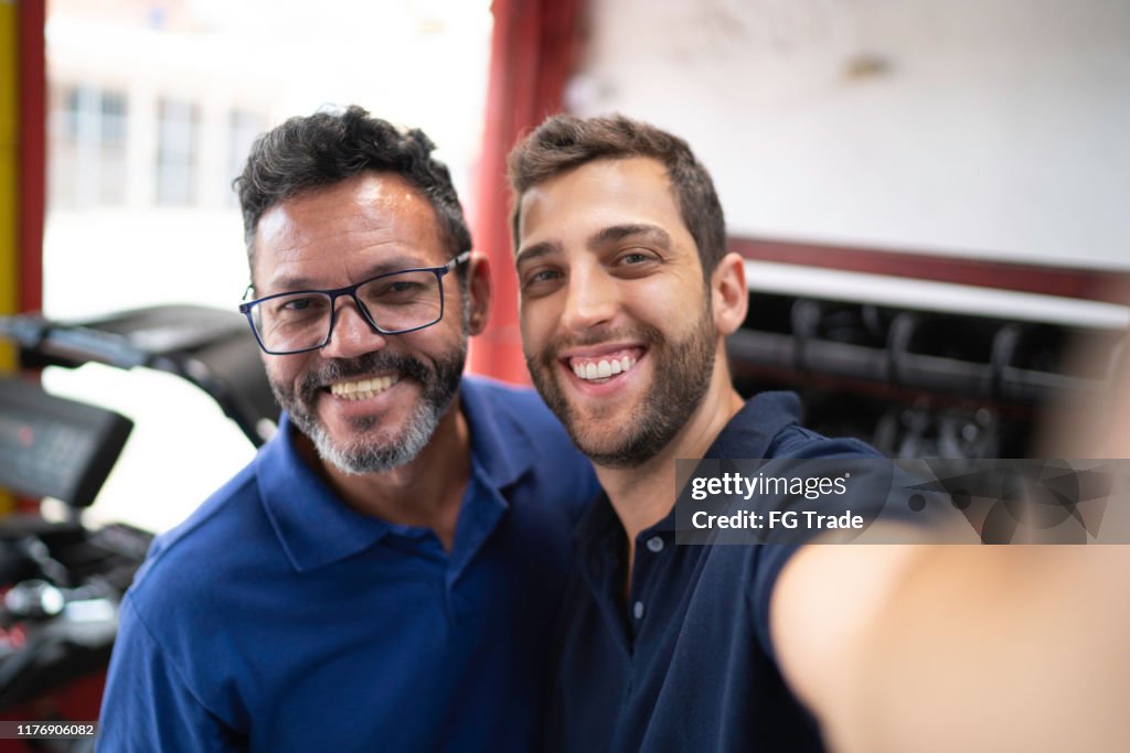 Mechaniker-Partner machen ein Selfie in Autowerkstatt