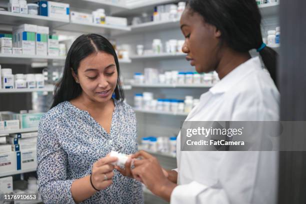 female pharmacist assists woman in pharmacy - pharmacist and patient stock pictures, royalty-free photos & images