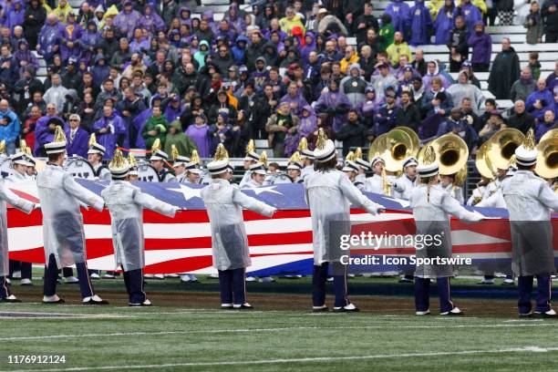 Washington band members dressed in rain gear held the American Flag up during the playing of the National Anthem before the college football game...