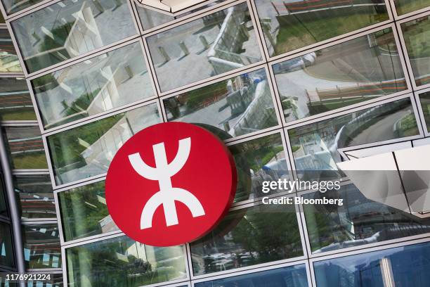Temporary fencing and water barriers are reflected in windows near the MTR Corp. Logo displayed at West Kowloon Station ahead of a protest in Hong...