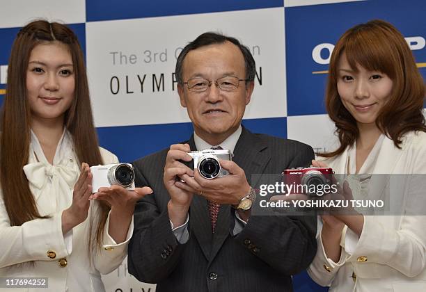Olympus Imaging president Syuichi Takayama and models display the new inter changeable lens digital cameras of Japanese camera giant Olympus "Pen...