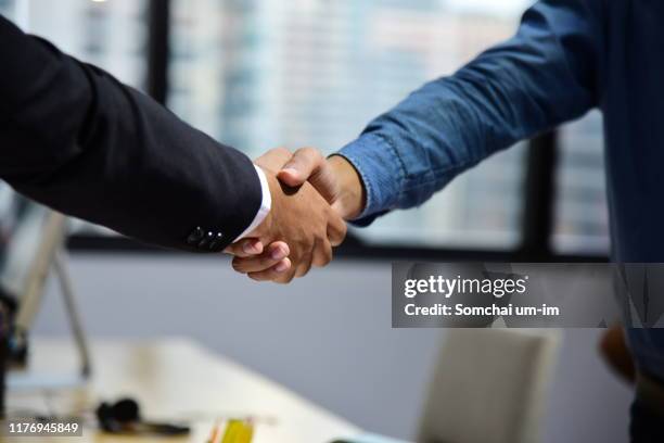 business people making agreement and shaking hands - contraer fotografías e imágenes de stock