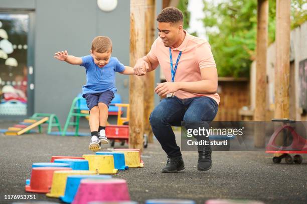 nursery worker with child in playground - nanny stock pictures, royalty-free photos & images