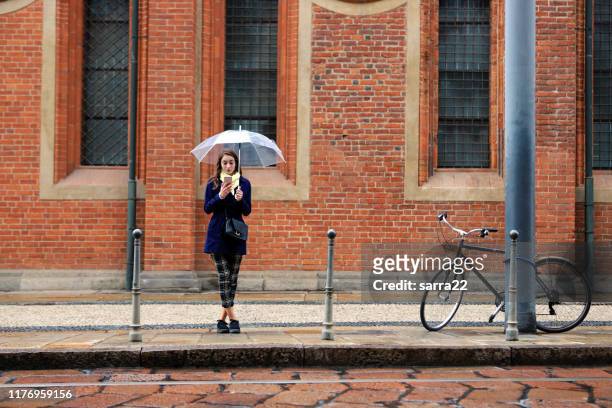 jonge vrouw met paraplu wachten - standing in the rain girl stockfoto's en -beelden