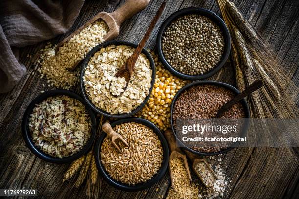 grande gruppo di cibo integrale girato su un tavolo di legno rustico - cereal plant foto e immagini stock