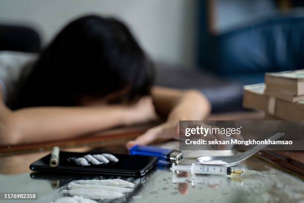 a drug addict with a syringe using drugs lying on the floor. the concept of anti drugs. male drug addict, drug syringe. - drug rehab stockfoto's en -beelden