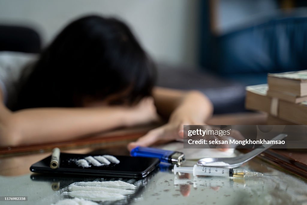 A drug addict with a syringe using drugs lying on the floor. The concept of anti drugs. male drug addict, drug syringe.