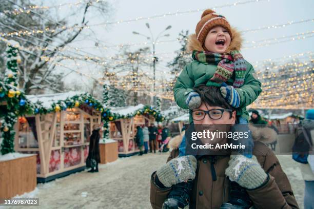 famiglia che cammina attraverso il mercatino di natale - mercatini di natale foto e immagini stock