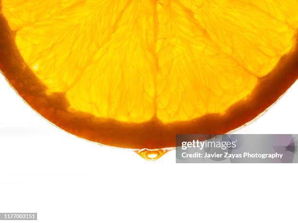 close-up of orange slice against white background - orange slice stock-fotos und bilder