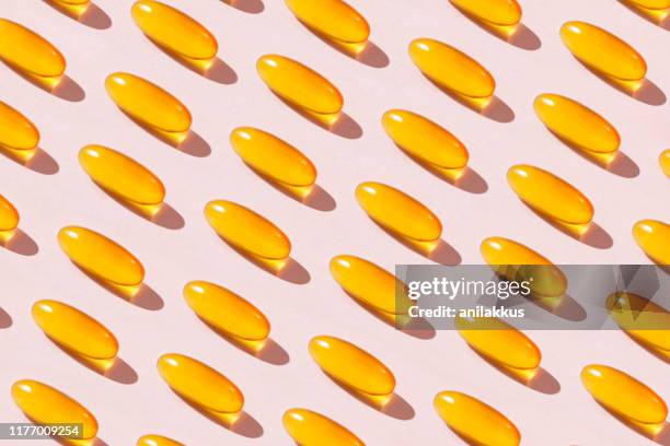 soft fish oil capsules on pink background - cod liver oil stock pictures, royalty-free photos & images