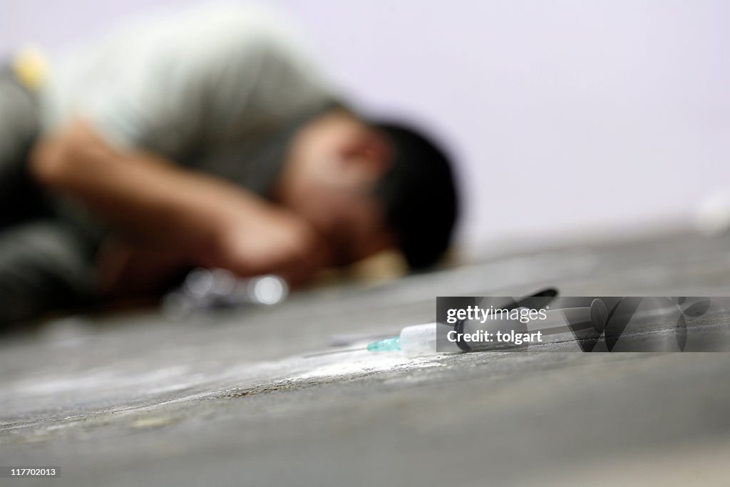 A man on the floor with a needle and drugs