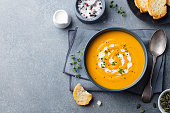 Pumpkin, carrot cream soup in a bowl. Grey background. Top view. Copy space.