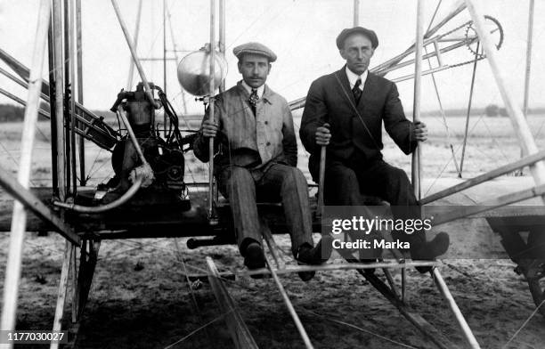 American aviation pioneer Wilbur Wright at the controls of his Wright Model A Flyer, alongside his passenger, the French balloonist and pilot Ernest...