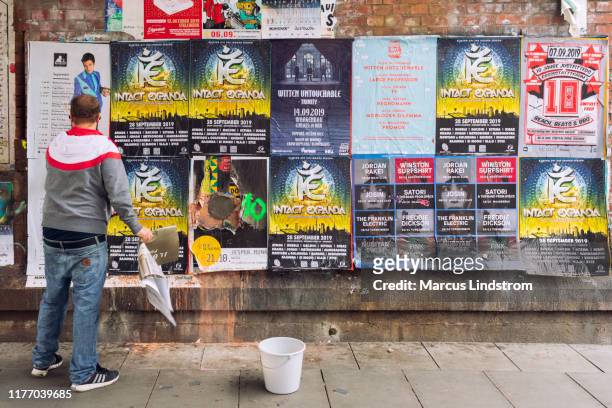 man putting up new posters on a wall - sticky stock pictures, royalty-free photos & images