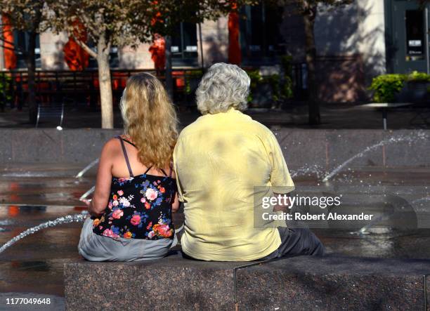 Man and women sit side-by-side in a park in downtown Denver, Colorado.