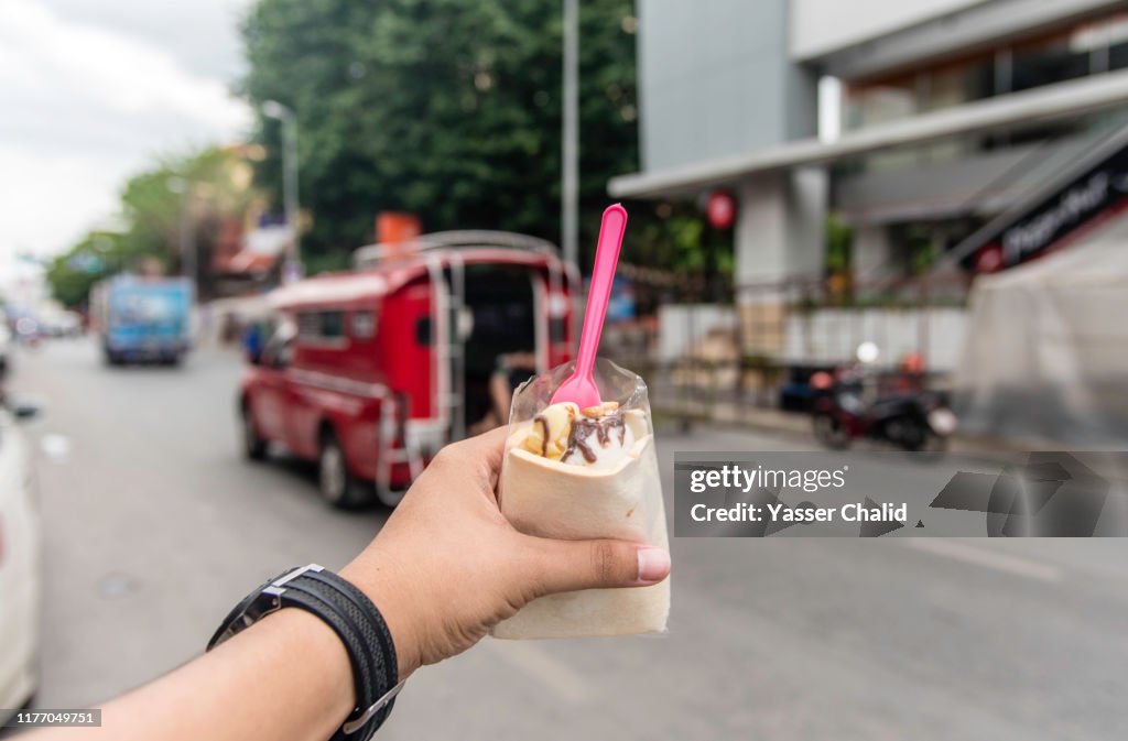 POV hand holding an ice cream sandwich on a street