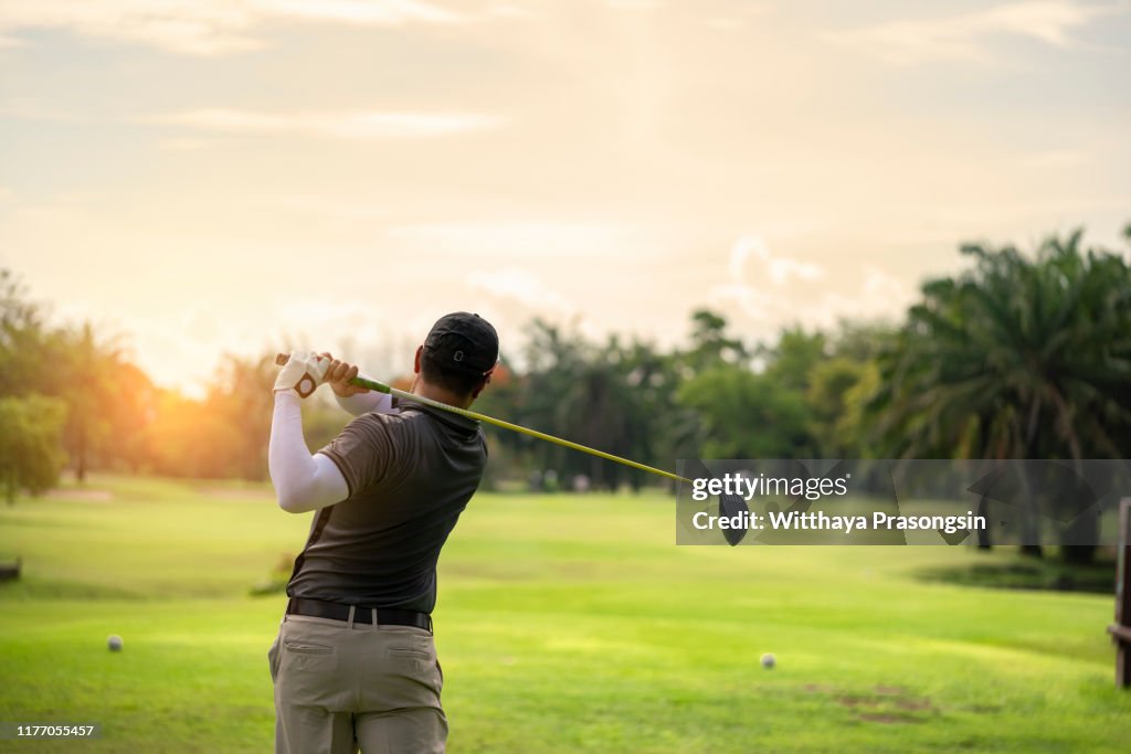 Golfer hitting golf shot with club on course while on summer vacation