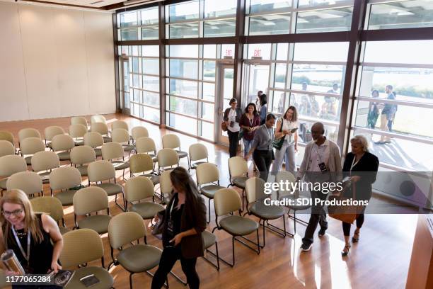 high angle view conference attendees filing into auditorium - town hall meeting stock pictures, royalty-free photos & images