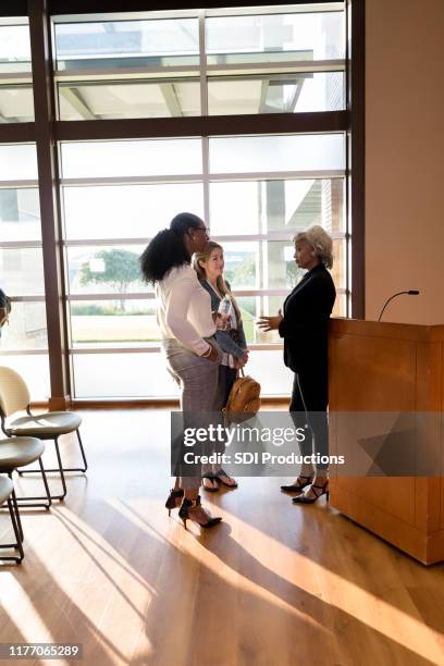 conference speaker meets with women after days events - diverse town hall meeting stock pictures, royalty-free photos & images