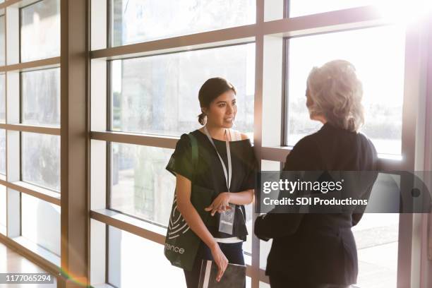 mid adult woman talks with speaker after conference - diverse town hall meeting stock pictures, royalty-free photos & images
