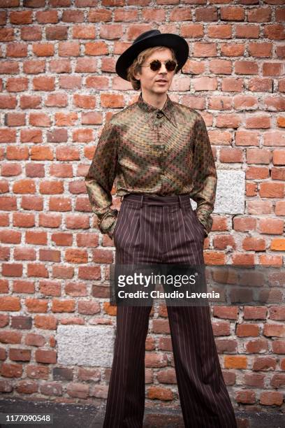 Beck Hansen, wearing printed shirt, brown striped pants and black hat, is seen outside the Gucci show during Milan Fashion Week Spring/Summer 2020 on...