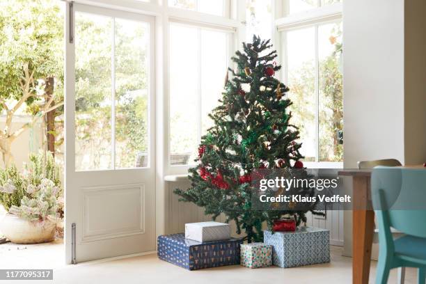 christmas tree with gift boxes by window at home - christmas tree presents stock pictures, royalty-free photos & images