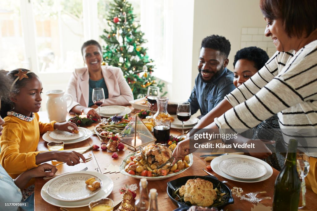 Woman cutting meat for family and friends on table