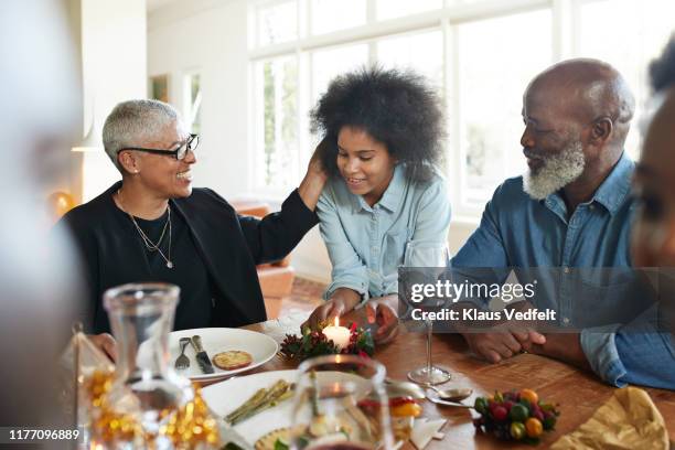 teenage girl talking with family at dining table - african american grandfather stock-fotos und bilder