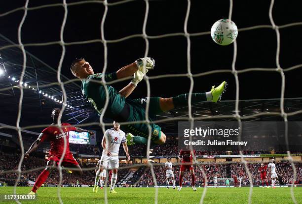 Stuart Moore of MK Dons makes a mistake as he tries to save a shot by James Milner of Liverpool which leads to a goal during the Carabao Cup Third...