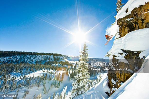 skier jumping cliff on sunny winter day. - aspen stock-fotos und bilder