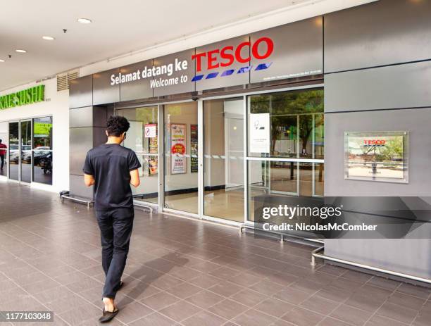 opinião traseira um homem novo que entra na loja de tesco na cidade penang de george - sliding door - fotografias e filmes do acervo