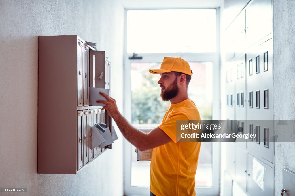 Postbote liefert Rechnungen in ApartmentBuilding Mailbox