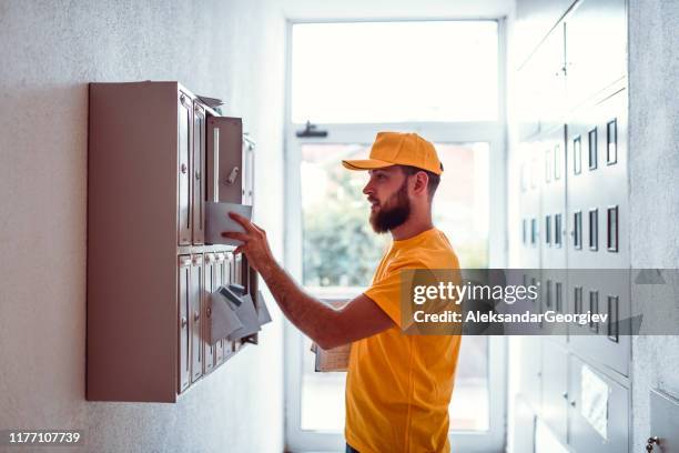 postbote liefert rechnungen in apartmentbuilding mailbox - mailman stock-fotos und bilder