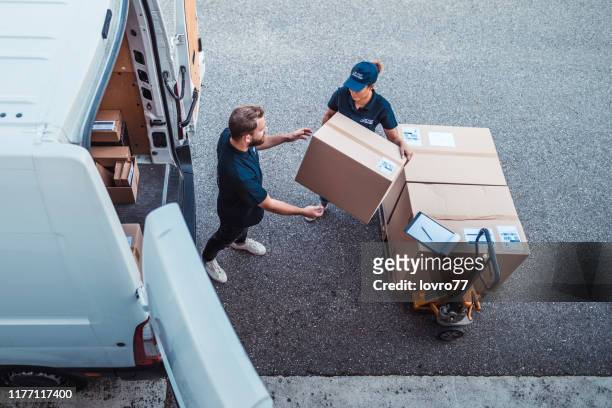 mitarbeiter eilen, um pakete in einen lieferwagen zu laden - freight transportation stock-fotos und bilder