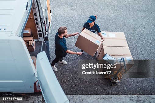 Coworkers rushing to load packages in a delivery van Coworkers rushing to load packages in a delivery van