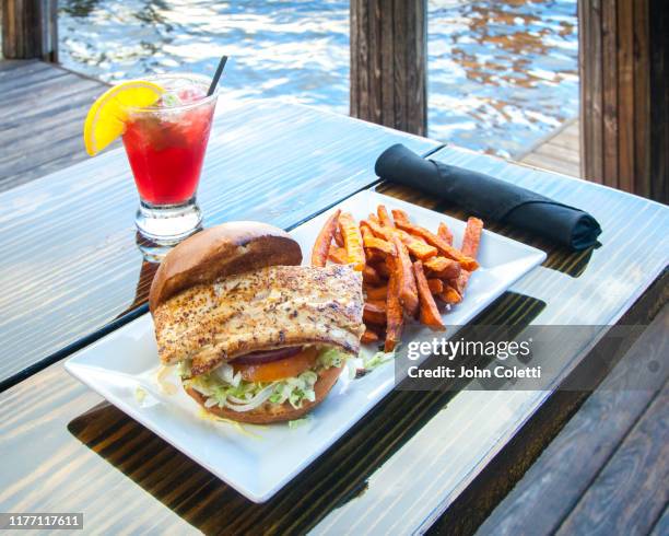 fish sandwich, french fries, red cocktail - tandbaars stockfoto's en -beelden