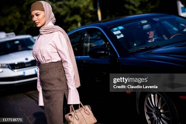 Neelofa, wearing a pink leather shirt, brown checked midi skirt, black boots and nude Tod's bag, is seen outside the Tod's show during Milan Fashion...