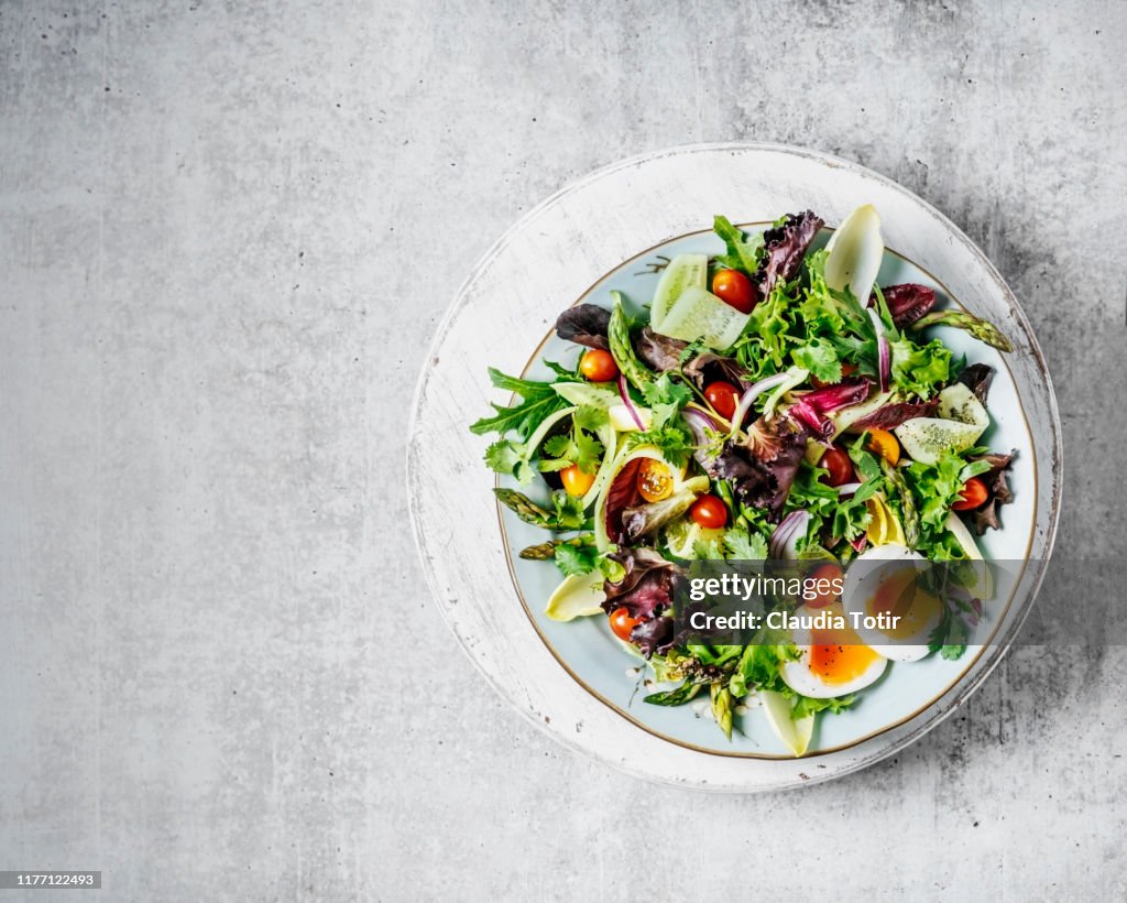 A plate of fresh salad on gray background