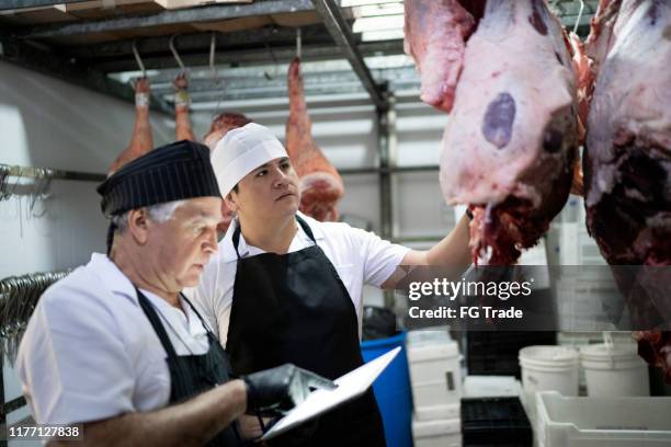 butchers using digital tablet to analyze products in a meat locker - meat factory stock pictures, royalty-free photos & images