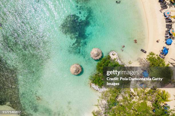 aerial top view of a tropical island beach with white sand and emerald water in roatan paradise island in the caribbean.. - strohgedeckte strandhütte stock-fotos und bilder