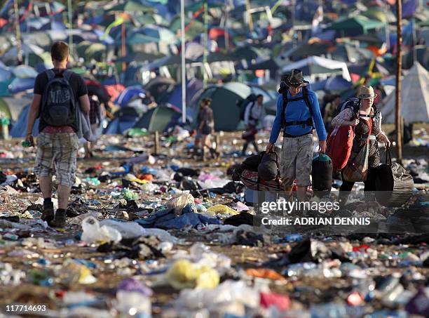 Festival-goers walk through rubbish close to The Pyramid Stage as they leave following the Glastonbury festival near Glastonbury, Somerset, on June...