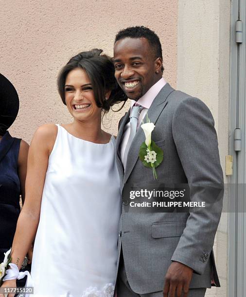 French football player Sidney Govou and his wife Clemence Catherin pose as they leave the church at the end of their wedding ceremony on June 18,...