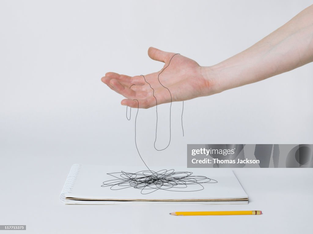 Hand holding pencil lines that turn into thread