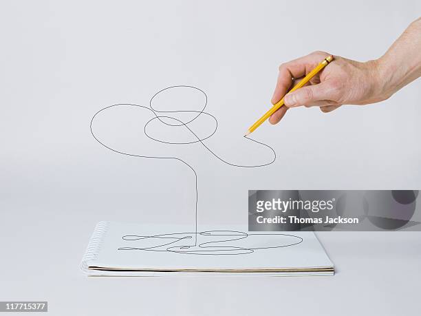 hand with pencil drawing off page - creación fotografías e imágenes de stock