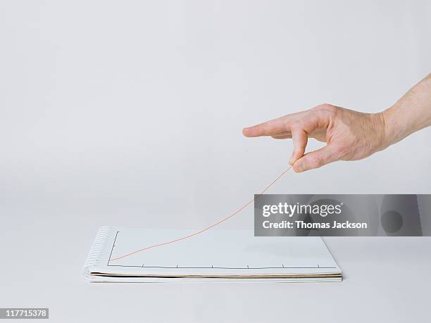 hand elevating graph line off the page - pick up paper stock pictures, royalty-free photos & images