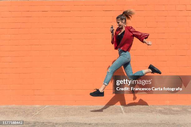 happy young woman running to school - running midair stock-fotos und bilder